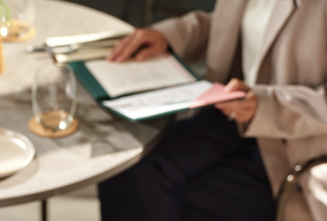 Guest browsing the dining menu at Kee’s restaurant in 21 Carpenter Singapore, seated at a marble table with contemporary tableware and warm interiors.